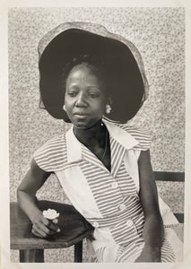 Seydou Keita - A seated woman wearing a 1950s western style dress flora with a black capi