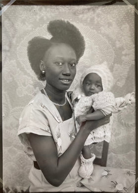 Seydou Keita - A young mother with her baby in her arms, in a western dress and wearing a bun